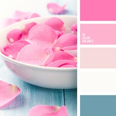 a white bowl filled with pink petals on top of a table