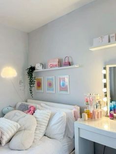 a white bed sitting in a bedroom next to a mirror and desk with lights on it