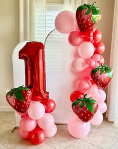 a number one balloon arch with balloons and strawberries