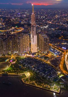 an aerial view of a city at night with the lights on and buildings lit up