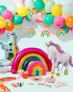 an assortment of party supplies including balloons, streamers and unicorn figurines