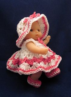 a small doll wearing a pink and white crocheted dress