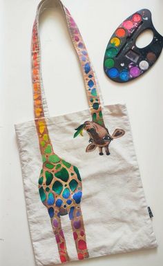 a tote bag with a giraffe painted on it next to a paintbrush