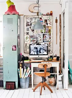 a room with a desk, refrigerator and pictures on the wall