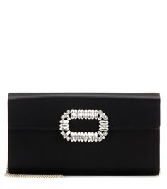 Roger Vivier is back with another covetable, convertible clutch. Crafted in Italy from smooth, lustrous black satin, this piece features a signature, eye-catching crystal embellishment to the front. Wear over the shoulder or simply tuck in the strap for a chic evening clutch. | Roger Vivier Evening Envelope satin clutch Roger Vivier Bag, Roger Vivier Clutch, Satin Clutch, Embellished Clutch, Luxury Clutch, Satin Noir, Velvet Boots, Evening Handbag, Black Clutch