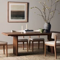 a dining room table with chairs and a vase filled with flowers on top of it