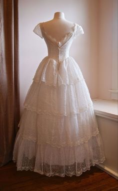 a white dress sitting on top of a mannequin in front of a window