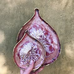 a hand is holding a decorative dish in the shape of a flower