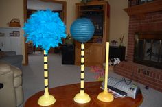 two tall yellow and blue vases with feathers on them sitting on a table in front of a fireplace