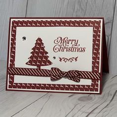 a merry christmas card with a bow and tree on the front, sitting on a wooden surface