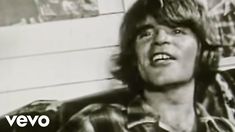 an old black and white photo of a man with long hair in plaid shirt looking up