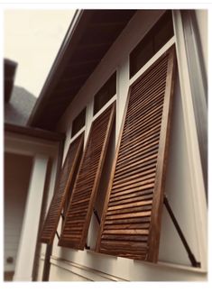 an open window with wooden shutters in front of a house