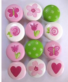 a bunch of pink and green buttons with hearts, flowers and butterflies on them in different colors