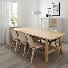 a dining table with four chairs and a rug on the floor in front of it