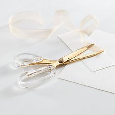 a pair of gold scissors sitting on top of white paper next to some tape and scissors