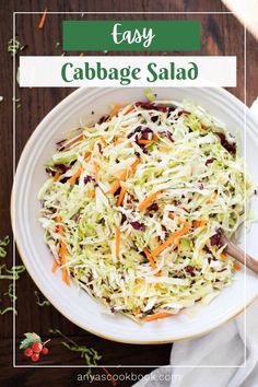 cabbage salad in a white bowl with carrots and cranberries on the side