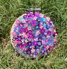 a wooden piece with flowers on it sitting in the grass