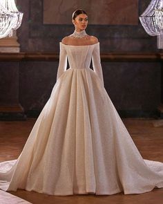 a woman in a wedding dress standing on a stage with chandeliers behind her