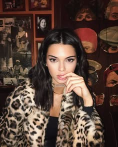 a woman in leopard print coat posing for the camera with her hand on her face