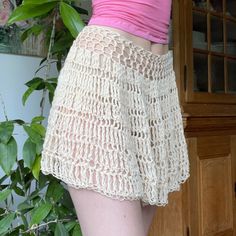 there is a woman wearing shorts with crochet on the bottom, and pink top