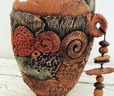 an artistic vase is adorned with beads and stones