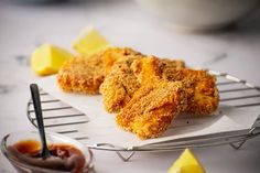 some fried food is sitting on a plate with sauce and lemon wedges next to it