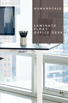 a desk with a computer monitor and keyboard on it in front of a window that reads humanscale laminate floating office desk