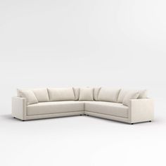 a white sectional couch with pillows on the top and bottom corner, facing away from the camera