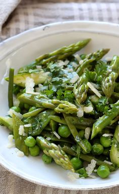 asparagus and pea salad with parmesan cheese on top in a white bowl