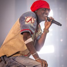 a man with a red hat on holding a microphone in his right hand and singing into the microphone