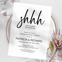 a white card with the word shhl on it next to some flowers and ribbons