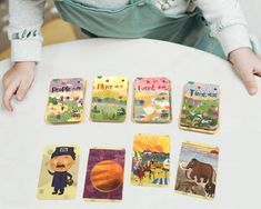 a child's hand holding onto some magnets with different pictures on them and an elephant in the background