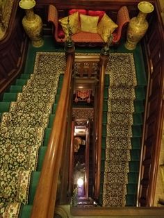 an overhead view of a stair case with green carpet and yellow pillows on the stairs