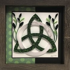 an intricate paper art piece in a wooden frame with green and white designs on it