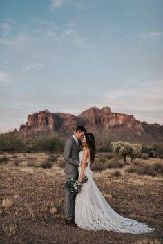 a bride and groom standing in the desert with mountains in the background at their wedding