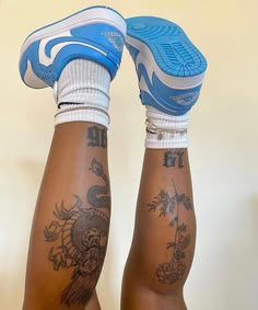 the legs and ankles of a person with tattoos on their bodies, both wearing blue shoes