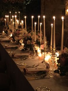 a long table with candles and flowers on it is set for a formal dinner or party