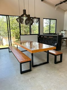 a table and benches in a room with large windows