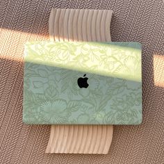 an apple laptop computer sitting on top of a wooden table next to a brown rug