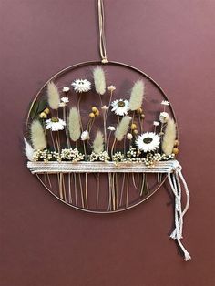 a metal rack with flowers on it hanging from the wall in front of a purple wall