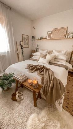 a bedroom with a white bed covered in blankets and pillows next to a wooden table