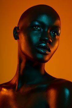 an image of a woman with black skin and gold paint on her face looking at the camera