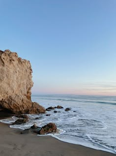 the beach is next to some large rocks