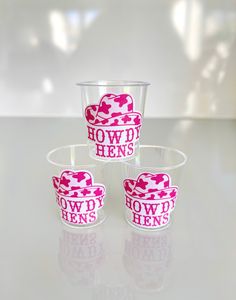 three shot glasses with pink and white designs on them