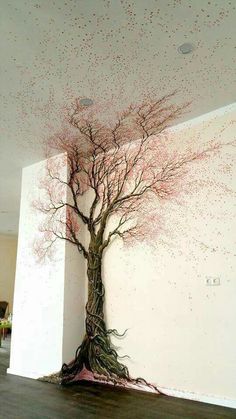 a large tree with pink leaves on it is in the middle of an empty room