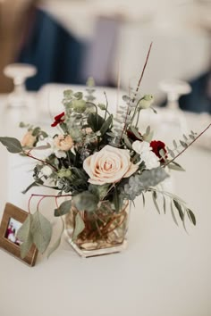 a vase filled with lots of flowers on top of a white table cloth covered table