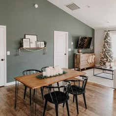 a dining room table with candles on it in front of an open door and christmas tree