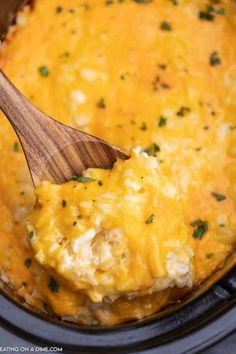 a wooden spoon in a crock pot filled with chicken and cheese casserole