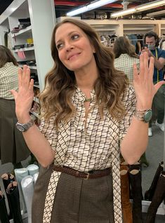 a woman standing in front of a mirror holding her hands up to the side with both hands