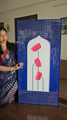 a woman standing in front of a blue and white frame with flowers on the side